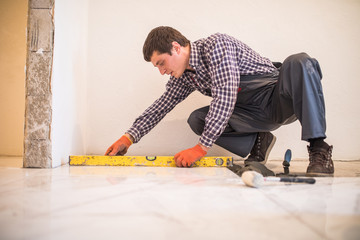 Fototapeta na wymiar Home tile improvement handyman with level laying down tile floor