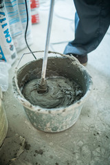 Mixing of a plaster solution by an electric drill. Home renovation. Workers mixed tile adhesives in buckets