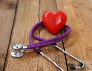Heart with a medical stethoscope, isolated on wooden background