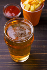 Beer with burger and fries on dark wooden background. Ale and food. View from above, top, vertical