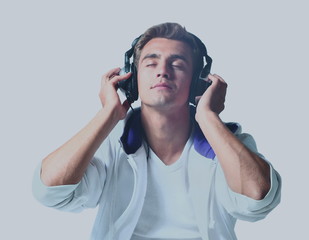 Portrait of a relaxed young man listening to music on headphone against white background