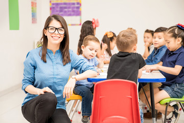 Portrait of a preschool teacher in a classroom loving her job