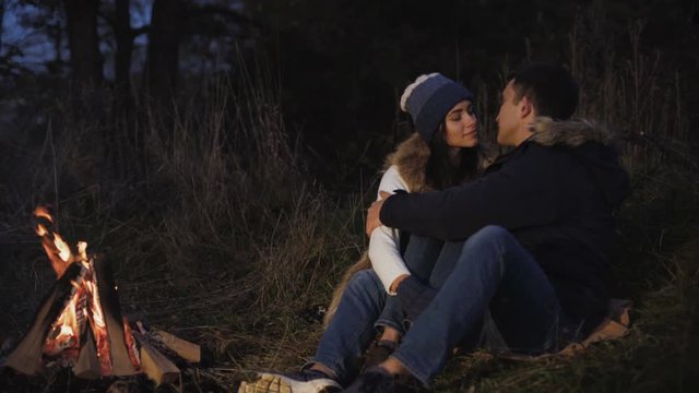 Romantic couple resting at bonfire, talking, kissing and caressing