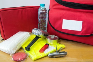 Emergency kit for survival in case of disaster including water, first aid kit, lighter, bags,...