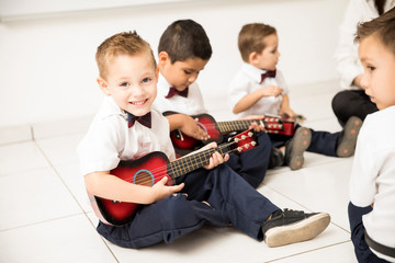 Cute boy learning how to play guitar