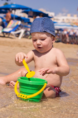 Cute kid playing on the beach with sand and water