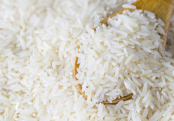 raw white rice in a wood spoon