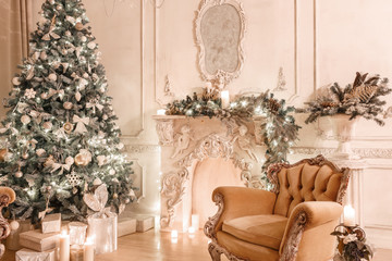 Christmas evening by candlelight. classic apartments with a white fireplace, decorated tree, sofa, large windows and chandelier.