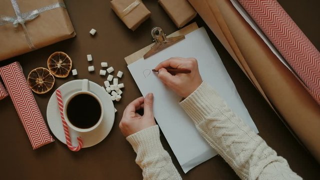 Christmas wish list writing. Woman creating present list for winter holidays. Top view, preparing for xmas and new year concept
