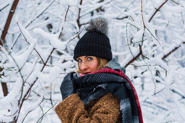 Beautiful blonde girl walking through winter forest