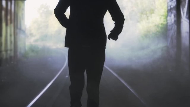 Slow motion man running away on train track. Back view. Abstract background shot. Concept of chasing the misty future.