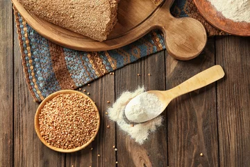  Buckwheat flour and raw grains in kitchenware on table © Africa Studio