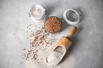 Fototapeta na wymiar Kitchenware with buckwheat flour and raw grains on table