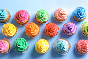 Delicious cupcakes on color background, top view