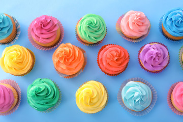 Delicious cupcakes on color background, top view