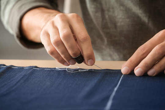 Young tailor working with textile, closeup