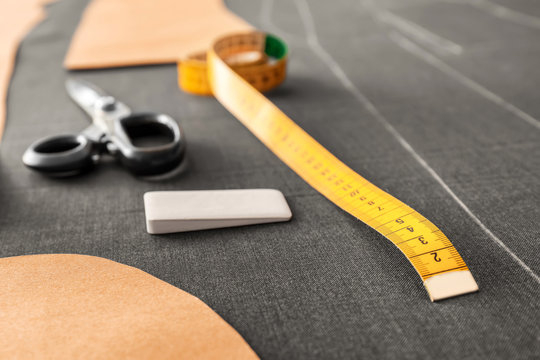 Measuring tape and tailor chalk on grey fabric, closeup