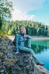 Девушка путешественник сидит на скале над озером в Черногории