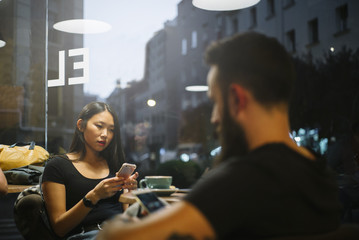 hipster man and asian woman in cafe bar.