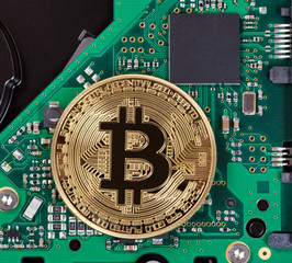 Gold Bitcoin with computer circuit board in background