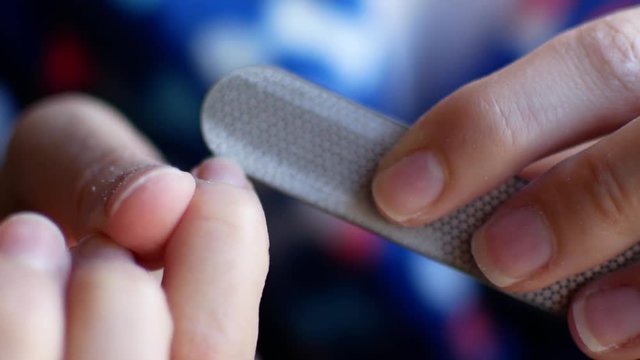 The girl does manicure at home. A woman is peeling her nails in her arms, close-up