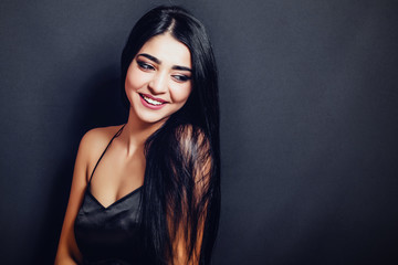 Beautiful woman with black straight hair  on a dark background smiling. Close-up. Space for text
