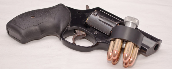 Obraz premium A black revolver with a loaded speed loader leaning against the barrel on a white background