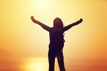 Fototapeta premium free female hiker with backpack standing on sunrise windy coast