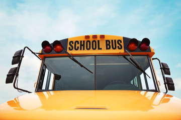  wide angle front view of a bright yellow orange school bus on a sunny summer day with clouds in the sky toned with a retro vintage instagram filter app or action effect © annette shaff