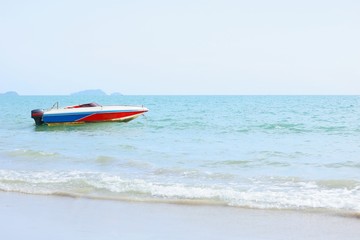 Old small motor boat at anchor by rope on beach, selective focus