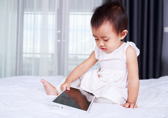 Fototapeta premium baby are looking to play and read tablet computer on bed