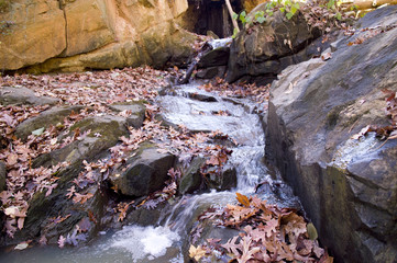 Autumn waterfall with fallen leaves