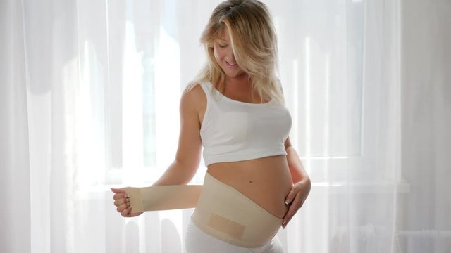 close-up of girl posing on the camera in a bandage for the comfort of pregnant women on white background