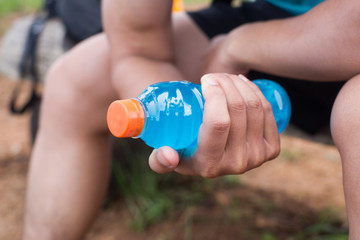 Marathon runner the bottle of blue energy water and orange energy water in the forest train running on race