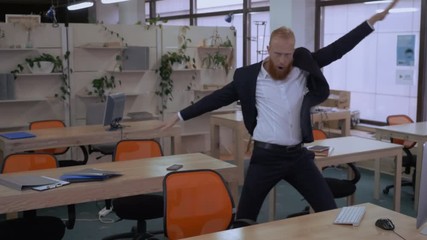 happy businessman dancing funny dance in empty office. ginger worker wearing elegant fashionable suit