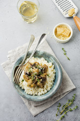Risotto with chicken and mushrooms, thyme, garlic, parmesan cheese on old gray concrete background. Traditional Italian dish. Selective focus. Rustic style. Top view.
