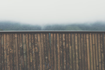 bamboo banister with view of fog & cloud on mountain in morning. mist on hill