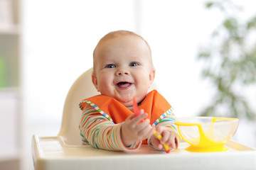 happy baby boy with spoon at table