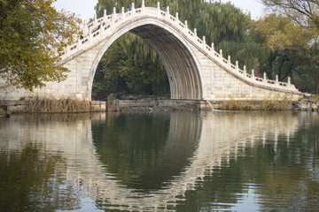 Fototapeta na wymiar The arch bridge and the inverted image on the water in Summer Palace