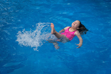 Young Girl Floating in Pool Making Splash with Her Legs