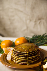Pancakes with oranges on a Christmas table with candles