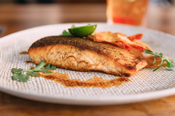 Close up Grilled well done salmon steak served with pistachio sauce and sliced lime topping with fried sticks.