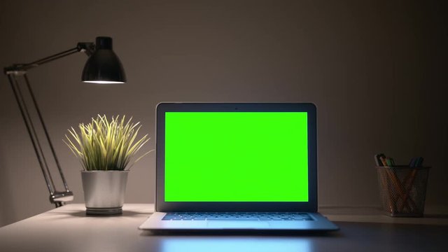 Green Screen Laptop display with a lamp on a wall background in Home Office.