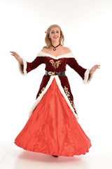 full length portrait of pretty blonde lady wearing red and white christmas inspired costume gown, standing pose on white background.