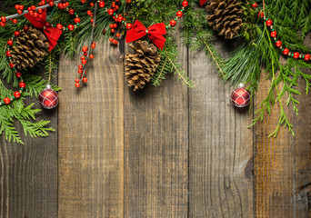 Christmas decorations and fir branches on wooden board background with copy space.