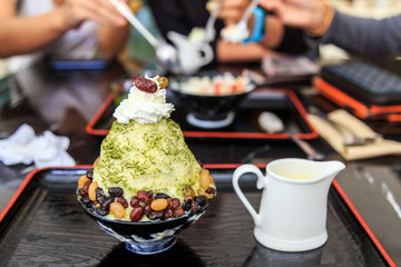 Bingsu green tea with sweet red bean on black cup and black tray.