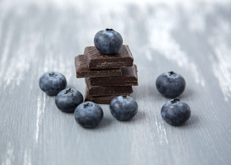 Close up Dark Chocolate Stack and Fresh Organic Blueberries on Wooden Background Natural Light Selective Focus