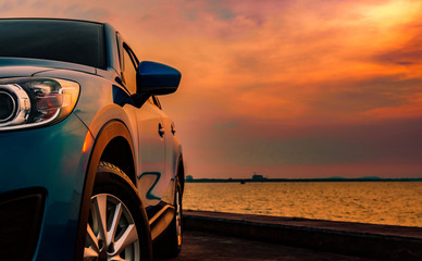 Blue compact SUV car with sport and modern design parked on concrete road by the sea at sunset. Environmentally friendly technology. Business success concept.