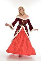 full length portrait of pretty blonde lady wearing red and white christmas inspired costume gown, standing pose on white background.