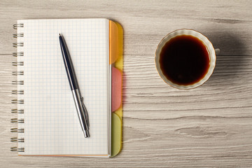 Notebook, pen and cup of coffee on a grey wooden background